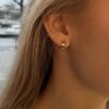 Øreringer brede i gult gull. Diameter 12 mm Bredde 4,3 mm, vist på modell