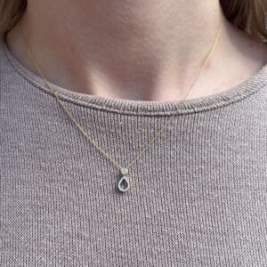 Anheng i gult gull. Oppe er det fattet en hvit topas og under er det et dråpeformet anheng med diamanter.