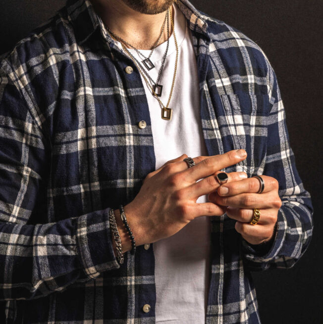 Signetring i sølv med rektangulær sort agat. Hjørnene på stenen er avrundet. Vist sammen med andre ringer, armbånd og kjeder.