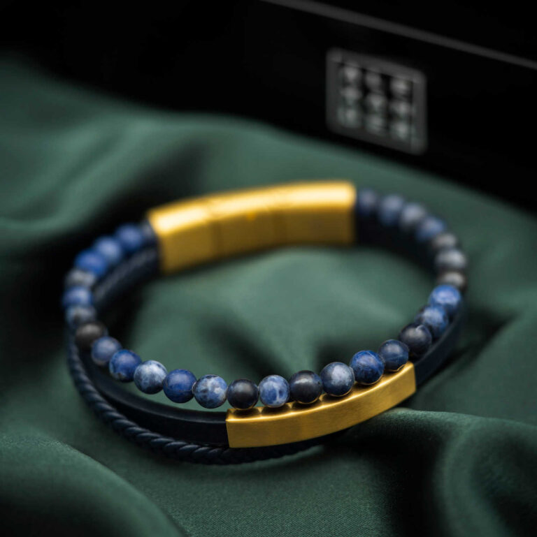 Armbånd i gullfarget stål, blått skinn og sten