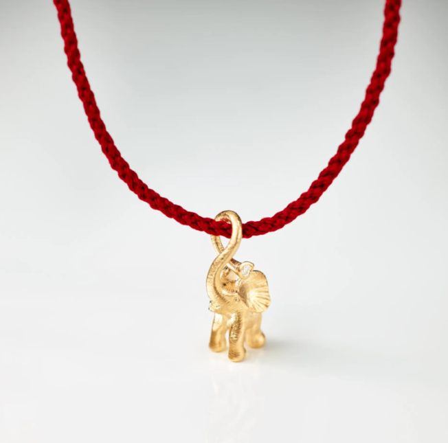 Liten elefant på rød snor som armbånd A2833- fra Ole Lynggaard. Laget i gult gull med diamant. Einersen Gull i Arendal. Gullsmed Arendal
