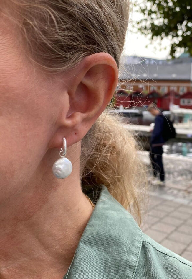Liten ørering i børstet sølv med mulighet til å henge på et heng, her med en flat ferskvannsperle