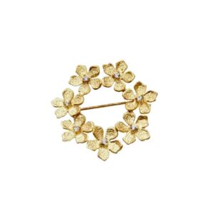 Brosje i forgylt sølv . Sirkel med 7 blomster. I hver av blomstene er det fattet en c.zirkonia. Catwalk Exclusive, 20 mm i diameter