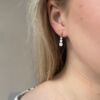 Ørepynt med 3 c.zirkonia i gult gull. Henger under en kule.. Vist på et øre.