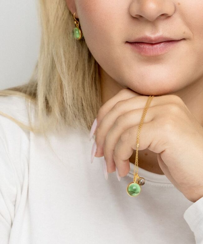 Anheng og ørepynt fra Julie Sandlau med grønn ametyst-farget krystall og LIttle Prime med røkfarget krystall anheng i forgylt sølv
