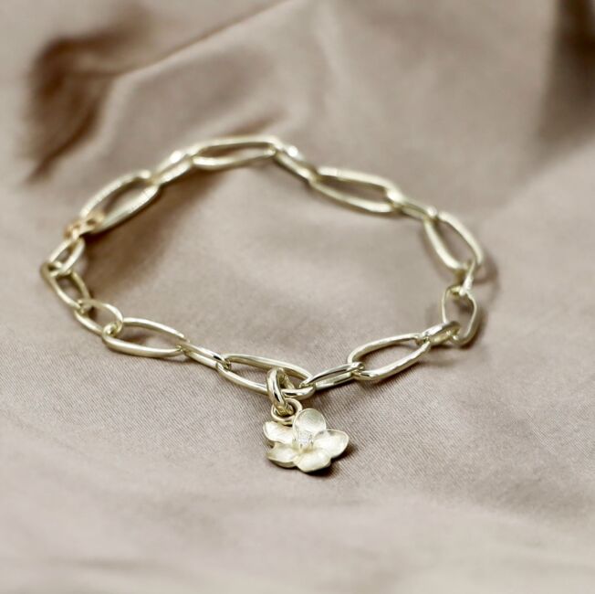 Blomsterserien til EC 1914 laget i Sandnes gult gull. Enkelt armbånd med åpne ringer med avtagbar blomstercharms med diamant i midten.