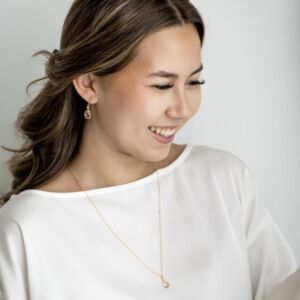 Ofelia ørepynt i forgylt sølv med krystall som er fasettslipt i en krok med en oval c.zirkonia som er fattet over. Fargen kalles Peach, Ferskenfarget. I tillegg anheng på kjede med krystall.